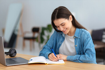 Distance learning, online education. Portrait of beautiful caucasian woman freelancer or student using laptop computer taking notes, watching training courses working from home or modern office