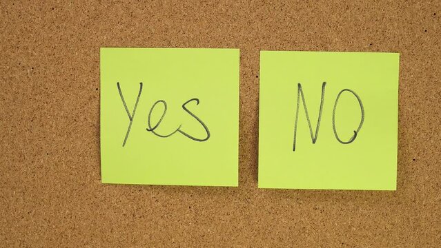 choice Yes or no Stick the sticker on the cork board. Top view of note agree or refuse. board. Wall of records in office. Leave a reminder at work or at home. Caucasian male hand unsticks paper.
