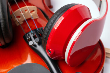 new bright red headphone speaker is placed on the violin. classical musical instrument