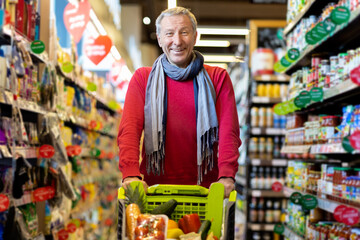 Happy senior man purchasing at supermarket alone
