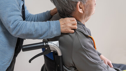 Fototapeta premium 車イスに乗った高齢者旦那の肩に手を置き介護する老人妻