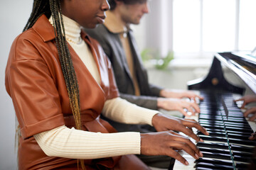 African young woman playing the piano together with her partner in team play during repetition at...