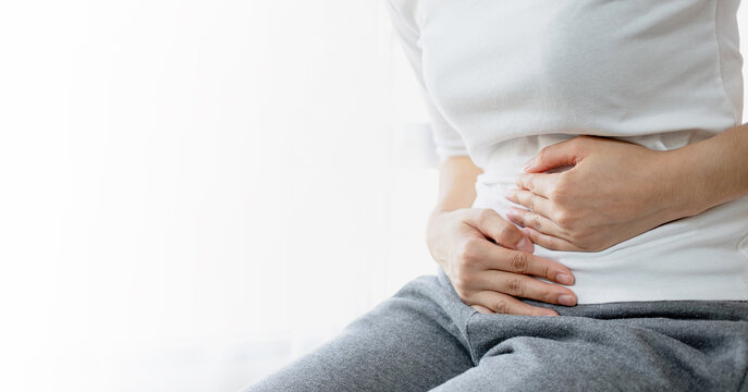 Young woman put her hand on her stomach because she had a very bad stomachache. menstrual pain, gastritis or diarrhoea. Healthcare medical concept.