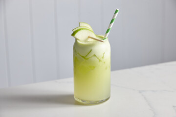 Glass of fresh apple juice with apple pieces and straw