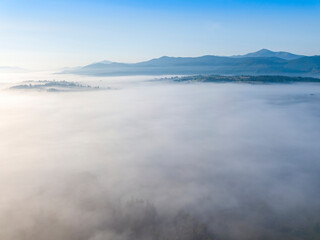 Fototapeta na wymiar Flight over fog in Ukrainian Carpathians in summer. Mountains on the horizon. Aerial drone view.