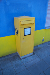 Single German post box in front of blue wall