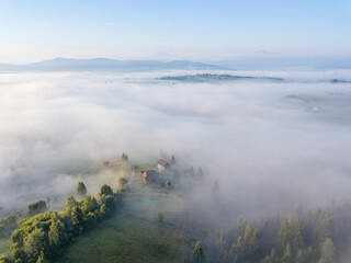 Fototapeta na wymiar Fog envelops the mountain forest. The rays of the rising sun break through the fog. Aerial drone view.