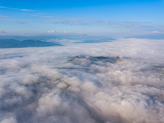 High flight above the clouds in the mountains. Aerial drone view.