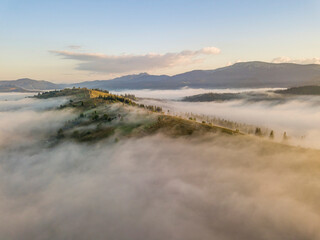 Mountain settlement in the Ukrainian Carpathians in the morning mist. Aerial drone view.