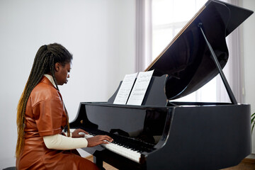 African female pianist concentrating on her play on the grand piano, she studying at musical school