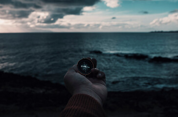 Travel adventure lifestyle concept with man holding navigation compass in front of dramatic sky and...