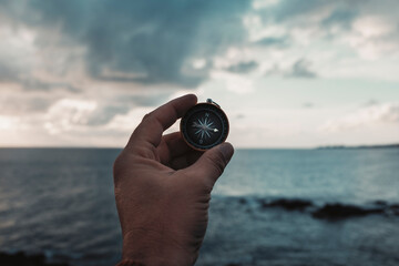 Pov of man hand holding navigational travel compass to find direction and next destination place....