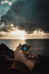 Travel adventure lifestyle concept with man holding navigation compass in front of dramatic sky and...