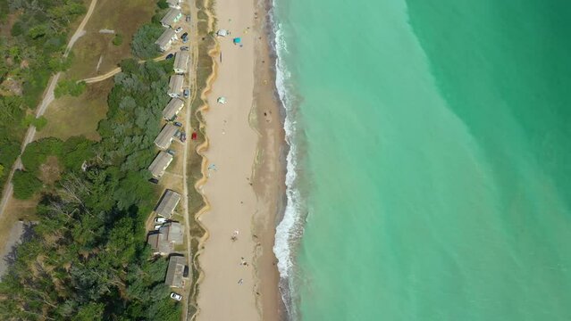 Aerial view of the beach filled with people on a hot sunny day. Sun umbrellas stand in yellow bright sand. Drone flying above the beach in Shabla, Bulgaria