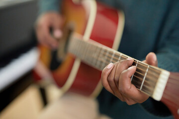 Close-up of student holding the guitar and learning the chords to play the melody during lesson