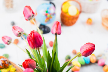 easter colorful eggs with tulips and spring flowers on a white wooden background