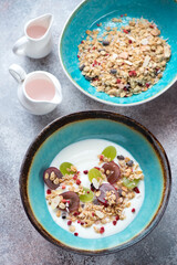 Turquoise bowls with greek yogurt, granola and grapes, high angle view on a roseate metal background, vertical shot