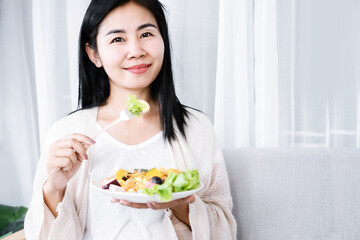 healthy Asian woman eating salad hand holding fork with vegetables in dish