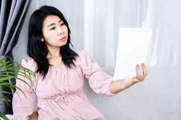 Asian woman having problem with farsighted trying to read text on book with eyesight blurred vision
