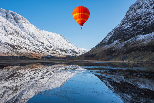 Digital composite image of hot air balloons flying over Stunning Winter landscape image of Loch Achtriochan in Scottish Highlands