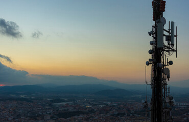 Telecommunications tower with cellular antennas and radar systems. Against the background of the evening sky over the tops of the mountains. Costa Brava, Catalonia