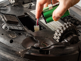 the serviceman changes the faulty battery in the robot vacuum cleaner.