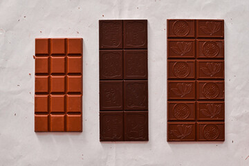 chocolate bars on white background top view, black, milk and white chocolate