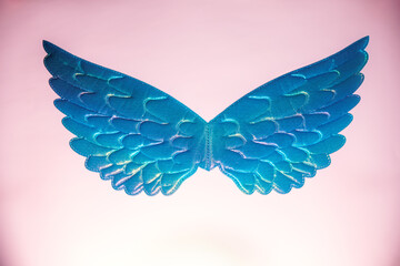Levitate glitter holographic toy wings against pink background. Concept of children Relief Foundation, funeral services.