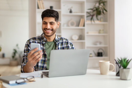 Portrait of smiling man using smartphone and pc at home