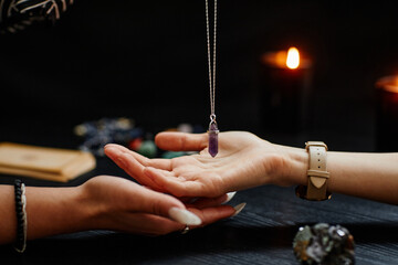 Side view closeup of fortune teller holding magic crystal over palm of young woman and reading her...
