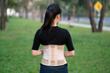young asian woman wearing back support for protect her back, medicine and healthy concept