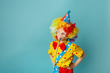 Funny kid clown against blue background. Happy child playing with festive decor. 1 April Fool's day...