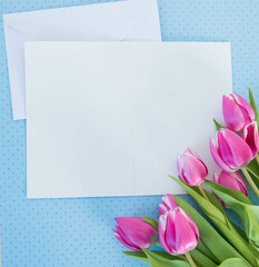 white card and envelope on blue ground with tulips with space for text