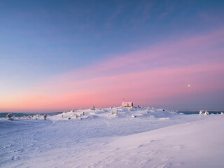 Cabin in winter. Dubldom on the mountain Volodyanaya Kandalaksha, Murmansk region in Russia. Holidays, vacations in winter. Beautiful Arctic sunset. Scenic colorful sky at dawn. Winter time.