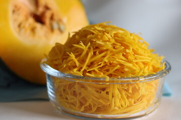Shredded pumpkin in a glass bowl. Shot along with a slice of pumpkin.