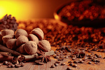 Chocolate truffles with cinnamon, anise, and coffee beans on a wooden table.