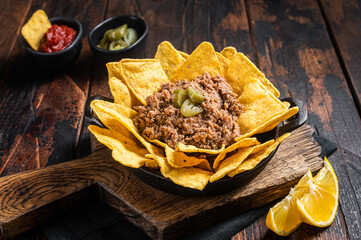 Mexican Baked nachos with chili con carne in a skillet. Wooden background. Top view