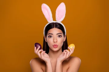 Foto op Aluminium Closeup photo of brunette asian ethnicity girl wear easter hare ears hold painted eggs send air kiss isolated pastel background © Beauty Hero