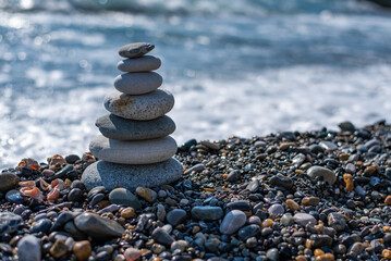 pyramid of stones balances on a pebble beach on a blurred background of the sea. concept meditation yoga zen