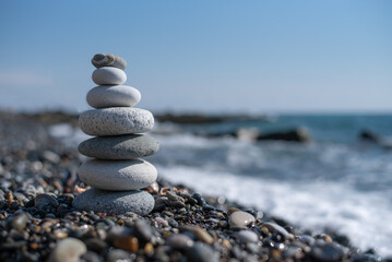 Fototapeta na wymiar pyramid of stones balances on a pebble beach on a blurred background of the sea. concept meditation yoga zen