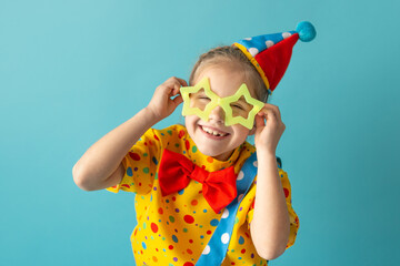 Funny kid clown against blue background. Happy child playing with festive decor. Birthday and 1...