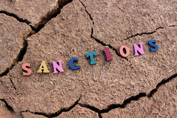 Wooden letters with the inscription: "Sanctions" on the cracked earth.The concept of the destruction of the state. Sanctions against the Russian Federation.