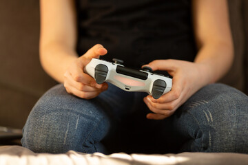 a girl playing a video game on a TV set-top box holds a joystick in her hands, selective focus