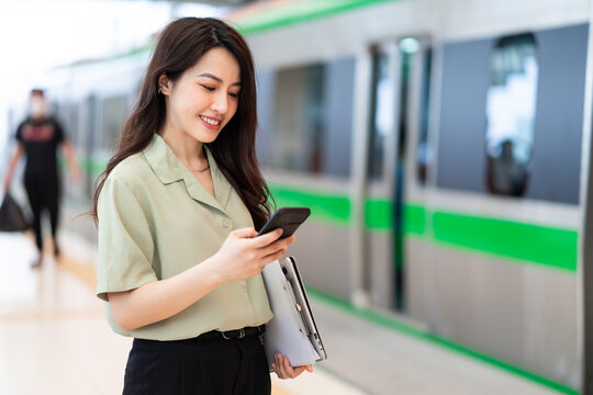 image of asian businesswoman using phone at train