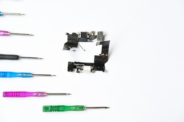 Printed circuit board pcb on a white background and a set of small colored screwdrivers for the...