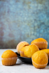 Close-up of small cupcakes on white wooden plate and table, selective focus, gray background, vertical, with copy space