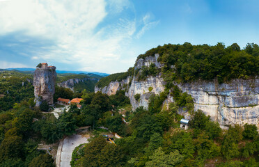 Naklejka premium Wide aerial panorama. Katskhi pillar. Georgian landmarks. Man's monastery near the village of Katskhi. The orthodox church and the abbot cell on a rocky cliff. Imereti, Georgia.vTravel and tourism