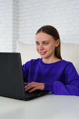smiling blogger girl communicates on the computer with her subscriptions. student studying online...
