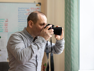 A photojournalist With A Camera In His Hands Takes Pictures Through the window