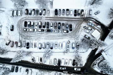 Top down aerial view of a parking lot full with cars in wintertime located nearby a ski resort 